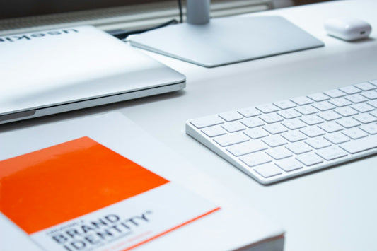 White and silver desk with a keyboard and one orange accent, photographed by Patrik Michalicka